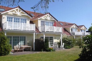 A row of two-story houses with balconies, a lawn, and outdoor furniture. - Buchengrund W 1 || Ostseebad Prerow (Ostseebad Prerow)