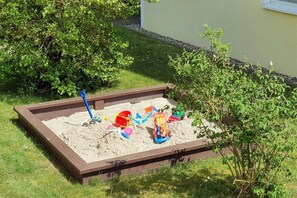 Ein Sandkasten mit Spielzeug und einer Schaufel.
