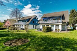 A residential area with two houses, one with a balcony and a satellite dish, and the other with a porch and outdoor seating. - Holiday apartment with 2 bedrooms (Prerow)