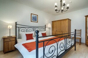 A bedroom with a bed, nightstands, a wooden wardrobe, and a chandelier. - Holiday apartment with 2 bedrooms (Prerow)