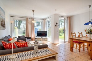 Ein modernes Wohnzimmer mit Sofa, Fernseher und Essbereich.