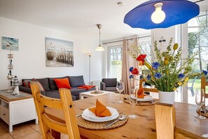 A dining area with a wooden table set for two, a sofa, and a painting on the wall. - Holiday apartment with 2 bedrooms (Prerow)
