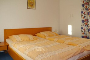 A double bed with a wooden headboard, a nightstand, and a single bedside table. - House "Am Brunnen" W.2 (Ostseebad Prerow)
