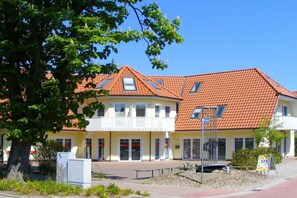 A two-story building with a red-tiled roof, multiple windows, and a paved entrance area with a sign indicating a price of 12 euros. - House "Am Brunnen" W.2 (Ostseebad Prerow)