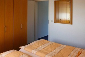 A bedroom with a bed, a wardrobe, and a mirror on the wall. - House "Am Brunnen" W.2 (Ostseebad Prerow)