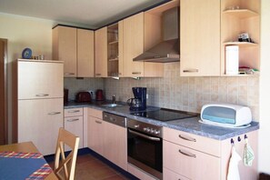 A kitchen with light wooden cabinets, a built-in oven, a coffee maker, and a toaster. - Grüne Str. 36 h "Seenadel" (Prerow)