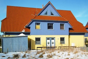 Un bâtiment à deux étages, avec un toit recouvert de tuiles rouges et une façade bleue et jaune.