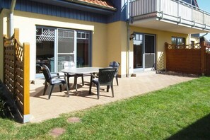 Une terrasse avec une table et des chaises, une porte-fenêtre coulissante et une clôture en bois.