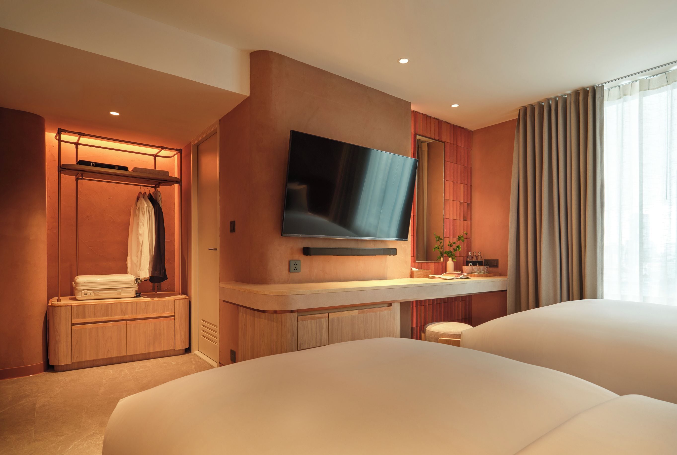 Een hotelkamer met een bed, een televisie, een kaptafel met spiegel en een inloopkast.