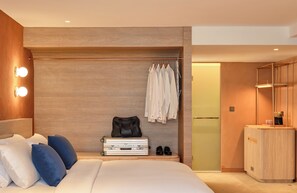 Habitación de hotel moderna con cama, lámparas de noche, armario y zapatero.