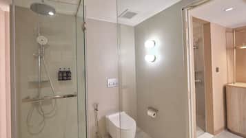 Ein modernes Badezimmer mit einer gläsernen Dusche, einer Toilette und einem Waschtisch mit Spiegel.