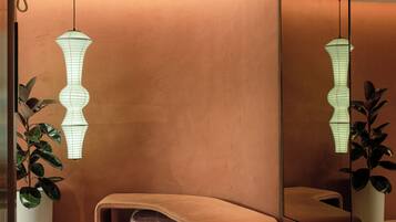 A modern interior with a curved bench, pendant lighting, and a large mirror.