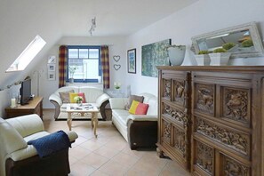 Ein Wohnzimmer mit einer Couch, einem Sessel, einem Couchtisch und einer Holzkabine mit Schnitzereien.