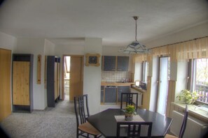 Ein Essbereich mit Tisch und Stühlen, eine Küche im Hintergrund und ein Fenster mit Blick.