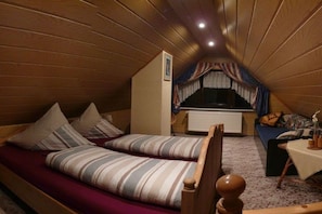 Ein gemütliches Schlafzimmer im Dachgeschoss mit einem Etagenbett, einem kleinen Sofa und einem Tisch mit einer Lampe.