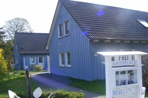 Ein blaues Gebäude mit der Aufschrift 'Ankerplatz', ein Schild mit 'Frei Ankerplatz' und 'Bebelstr. 12' sowie ein gepflasterter Weg zum Eingang.