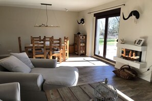 A living room with a sofa, wooden chairs, a fireplace, and a large window. - Time out - House by the lake, holiday home (Groß Kreutz)