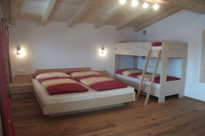 A room with a bunk bed, a single bed, wooden flooring, and wall-mounted lights. - Seber-Alpschwendthof family (Mittersill)
