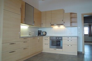 A modern kitchen with light wood cabinets, stainless steel appliances, and a built-in oven. - Seber-Alpschwendthof family (Mittersill)