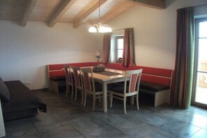 A dining area with a wooden table and chairs, a bench, and a chandelier. - Seber-Alpschwendthof family (Mittersill)