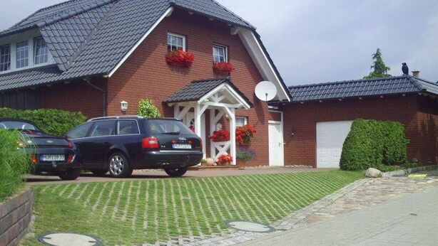 A two-story house with a garage, a driveway, and a satellite dish. - Holiday home with 1 bedroom (Waren \/ Müritz)