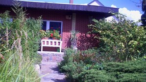 A red brick house with a stone pathway leading to a white bench. - Holiday home with 1 bedroom (Waren \/ Müritz)
