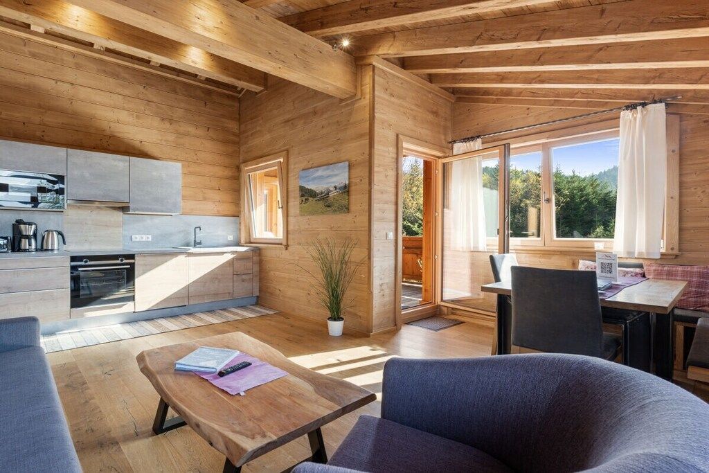 L’intérieur d’un chalet en bois comprend une cuisine, un coin repas et de grandes fenêtres.