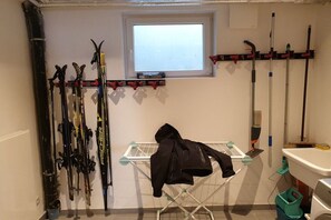 Ein Skiabstellraum mit Skiern und einer Jacke an einem Gestell, ein Fenster und ein Waschbecken.