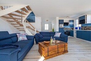 Ein zeitgemäßer Wohnraum mit Treppe, zwei Sofas, einem Couchtisch und einer Küchenzeile.