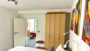 A bedroom with a bed, a wooden wardrobe, a desk with a chair, and a small stool. - Holiday apartment with 2 bedrooms (Waren (Müritz))