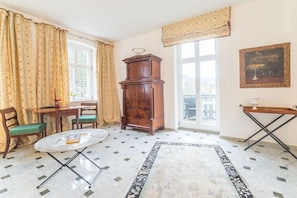 Ein Zimmer mit Esstisch, Stühlen, einem Schrank, einem Fenster und einem Bild an der Wand.