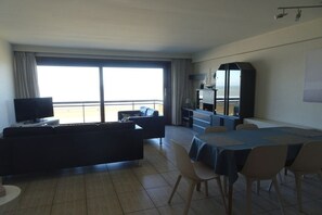 A hotel room with a balcony, a dining area, a sofa, a TV, and a minibar. - Holiday apartment with 2 bedrooms (Koksijde)