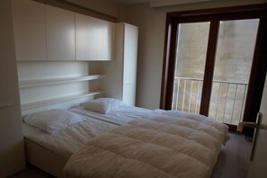 A bedroom with a bed, built-in shelving, and a balcony. - Holiday apartment with 2 bedrooms (Koksijde)