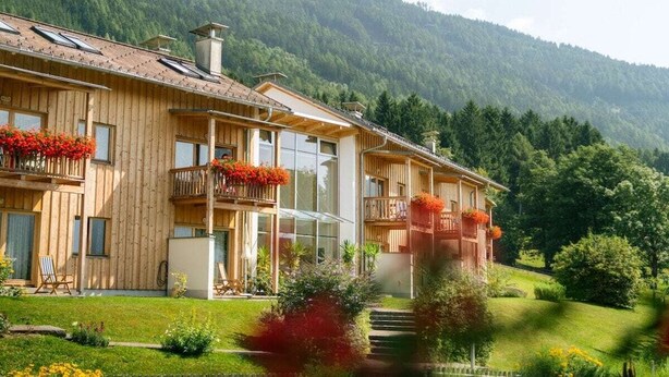 Un chalet en bois doté de nombreux balcons, de grandes fenêtres et surplombant un paysage montagneux.