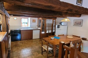 A kitchen with wooden cabinets, a stove, and a refrigerator. - Charming and spacious gîte with shared pool (Saint-Saud-Lacoussière)