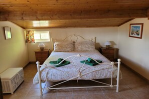 A bedroom with a metal-framed bed, two bedside tables with lamps, a window with curtains, and a picture on the wall. - Gîte with garden and shared pool (Saint-Saud-Lacoussière)