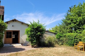 A rustic building with a wooden door and a small porch area. - Gîte with garden and shared pool (Saint-Saud-Lacoussière)