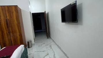 Habitación de hotel con cama, televisión montada en la pared y un pasillo que conduce a otra habitación.
