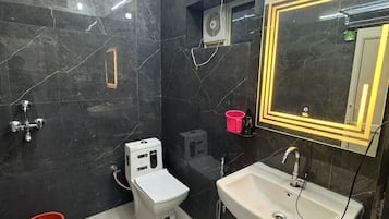 A modern bathroom with a toilet, bidet, sink, and a mirror with neon lights.