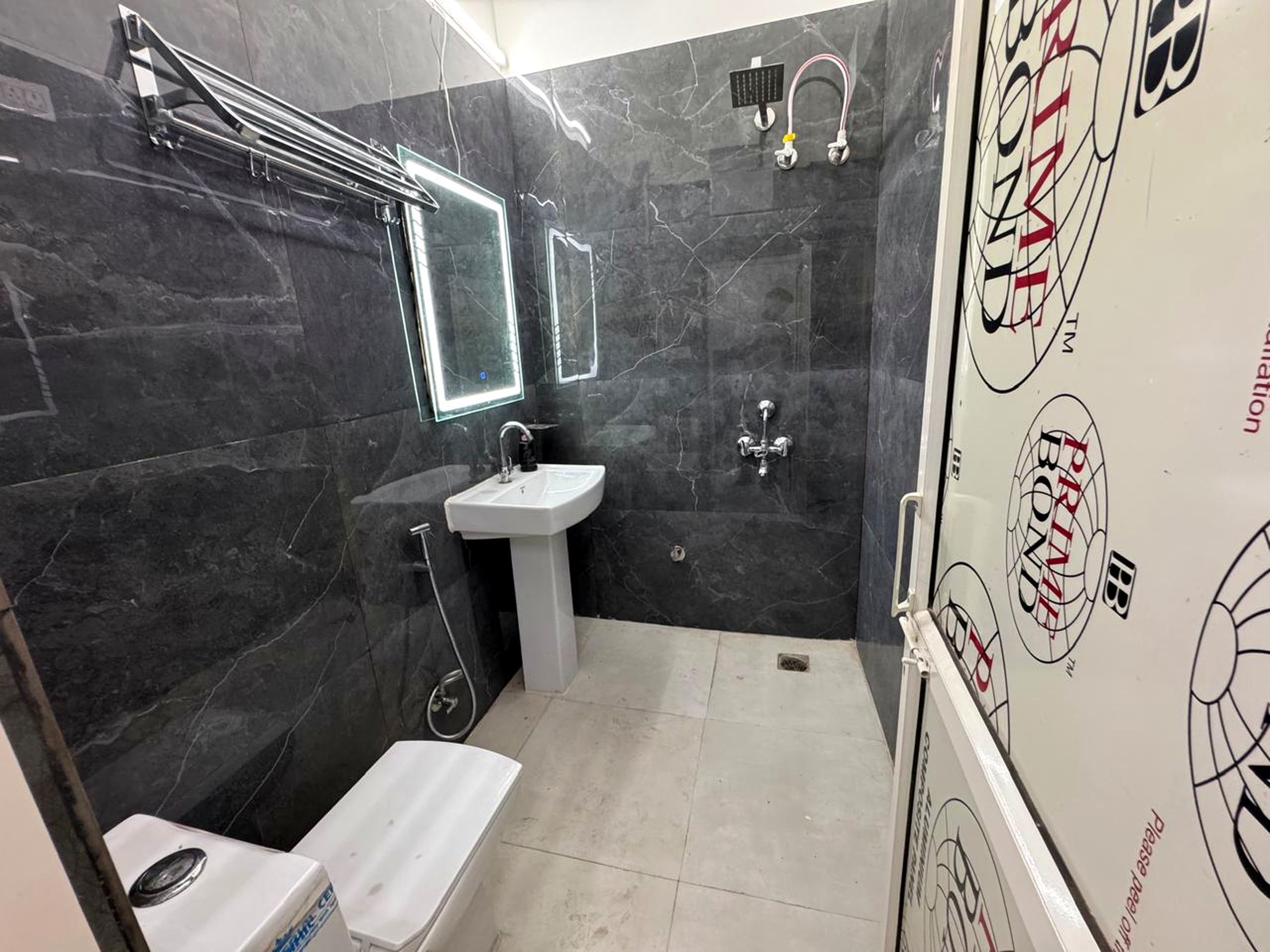 Ein Badezimmer mit weißem Waschbecken, einem Spiegel, einer Dusche und einer Toilette.