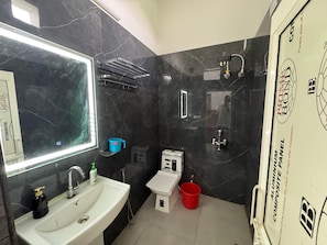 Un baño con lavamanos blanco, un espejo, inodoro y zona de ducha.