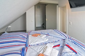 Un dormitorio con cama, mesita de noche, lámpara y puerta que da a una escalera.