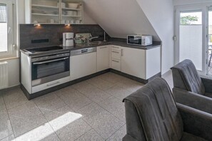 Uma cozinha compacta equipada com forno embutido, micro-ondas e máquina de café.