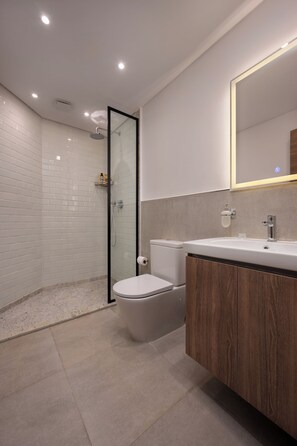 A modern bathroom with a glass-enclosed shower, a toilet, and a vanity with a mirror. - Lovely Home at Elevens by Spacey #33 (cairo)
