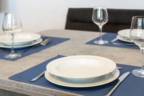A dining table with plates, cutlery, and wine glasses set for a meal. - Holiday apartment with 1 bedroom (Bensersiel)