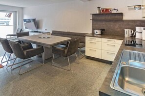 Et moderne køkken med spiseplads, inklusive et bord, stole og en indbygget ovn.