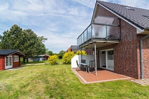A two-story house with a balcony, a brick exterior, and a grassy yard. - Holiday apartment with 2 bedrooms (Bensersiel)