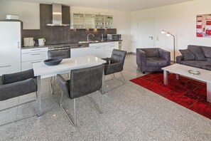 Une cuisine moderne avec des meubles blancs, une table à manger avec des chaises et un tapis rouge.