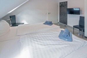 Een moderne hotelkamer met twee bedden, een flatscreen-tv en een zithoek.