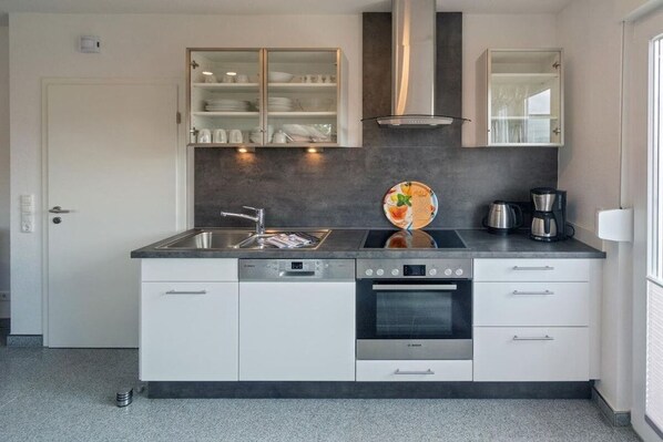 Eine moderne Küche mit Geschirrspüler, Backofen und Kaffeemaschine.
